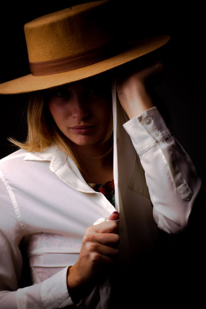 一个年轻女孩的照片在一个棕色的帽子举着一个白色衬衫的领子图片下载