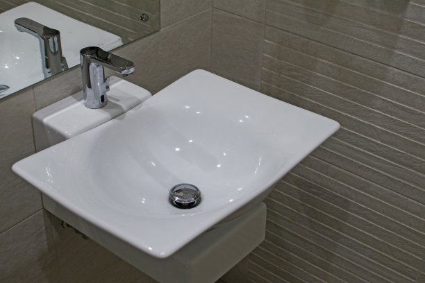 厨房台面洗脸盆在一个现代化的浴室。浴室里有水龙头的陶瓷脸盆。浴室内饰有水槽和水龙头。图片下载