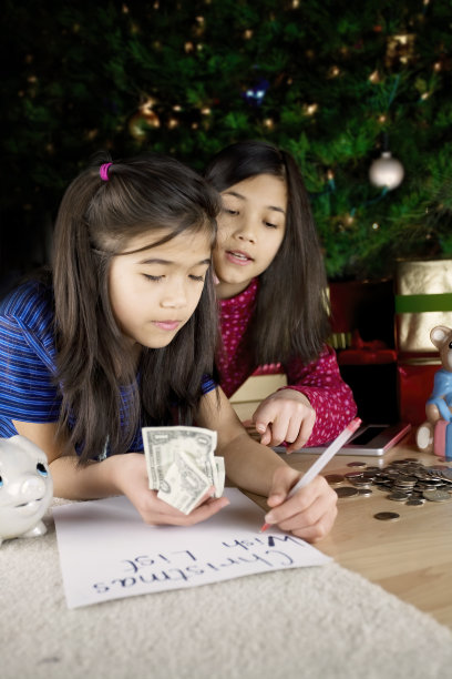 两个女孩在圣诞树下写愿望清单图片下载