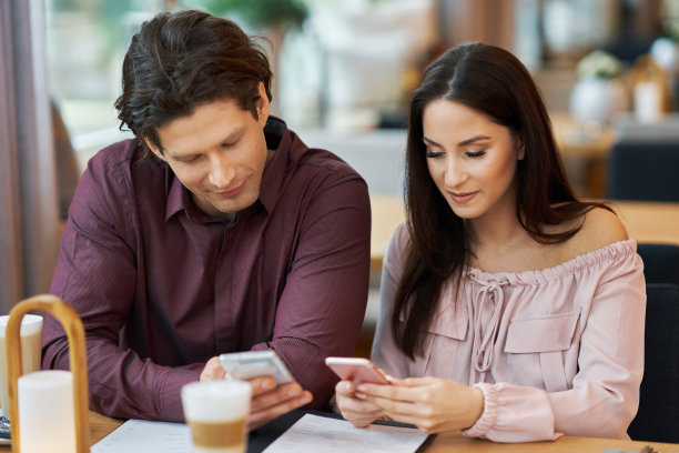 年轻夫妇在咖啡馆使用智能手机图片下载