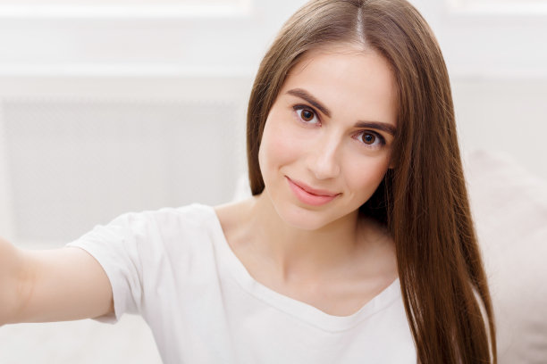 漂亮微笑的女孩在自拍，长头发的黑发在白色的衣服，特写图片下载