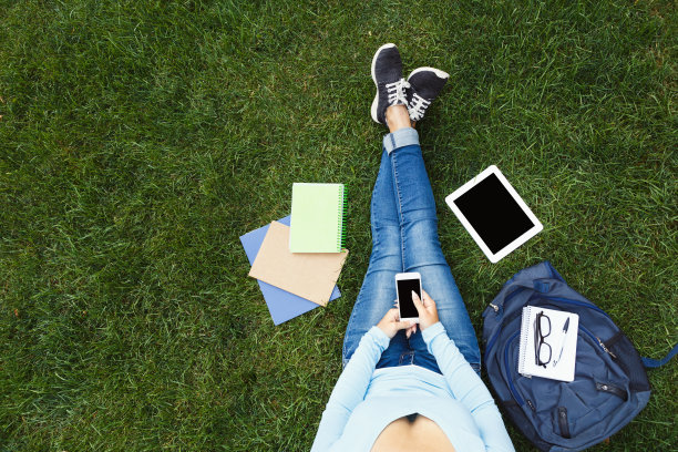 草地上拿着手机的女孩图片下载