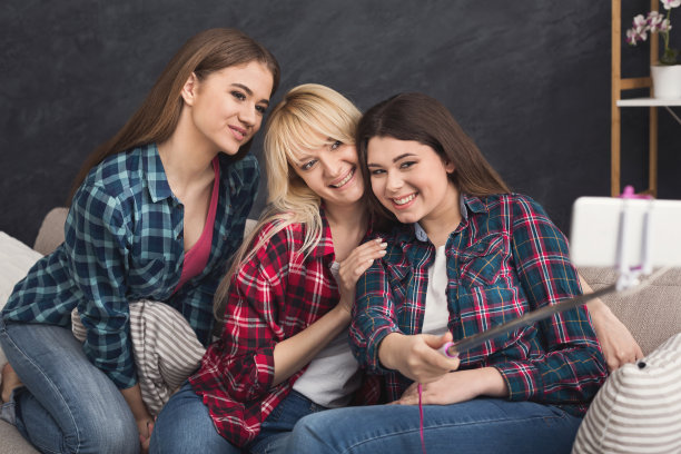 快乐的朋友用智能手机和单脚架自拍图片下载