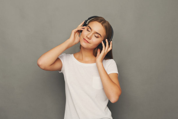 女人戴着耳机听音乐，在录音棚拍摄图片下载