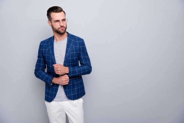 照片中严肃沉思沉思的男人正在系袖子上的扣子，他穿着白色裤子，戴着孤立的灰色背景眼镜，沉思地看着空荡荡的空间图片下载