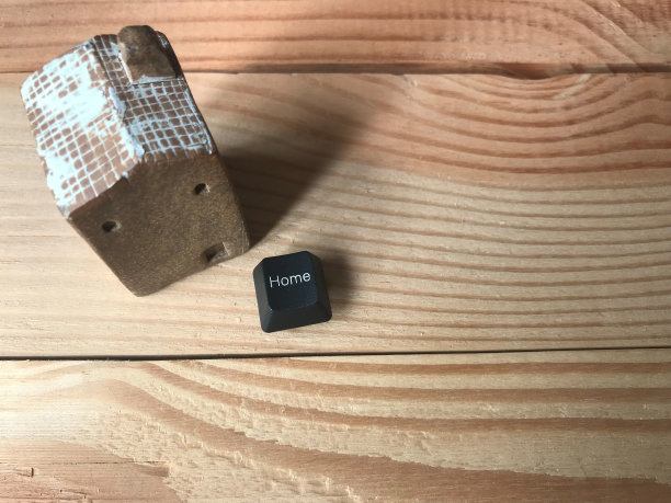 顶视图工作室拍摄的白色屋顶陶瓷房子与家庭黑色按钮从电脑键盘放在天然橡胶木桌子上图片下载