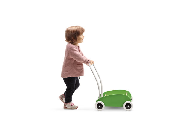一个蹒跚学步的女孩推着一辆玩具车的完整的侧面照片图片下载
