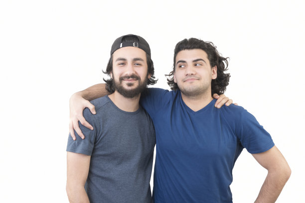 两个男性朋友在白色背景下拥抱着看着相机图片下载