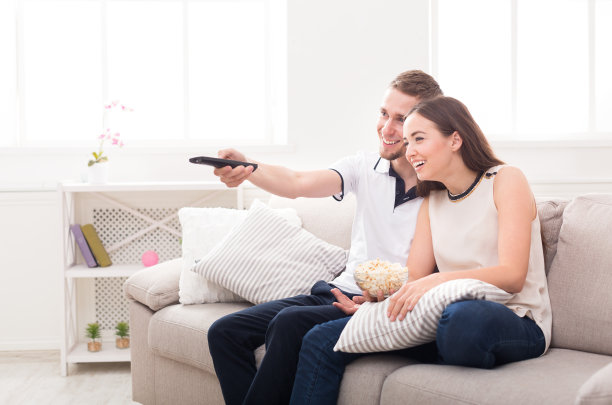 微笑的年轻夫妇在家里看电视图片下载