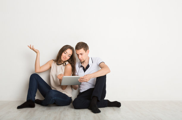 一对震惊的夫妇坐在地板上用笔记本电脑图片下载
