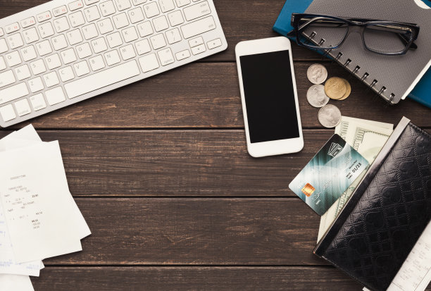 木桌上放着钱和智能手机图片下载