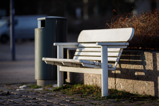 城市里的白色长凳。街道背景上的长凳，背景上有一个骨灰盒。图片下载