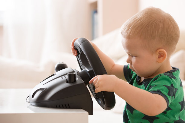 可爱的小男孩玩电脑方向盘，准备成为专业司机图片下载