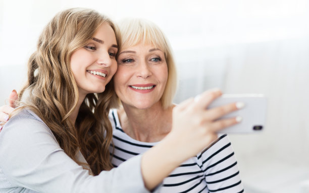 迷人的博主用智能手机和妈妈自拍图片下载