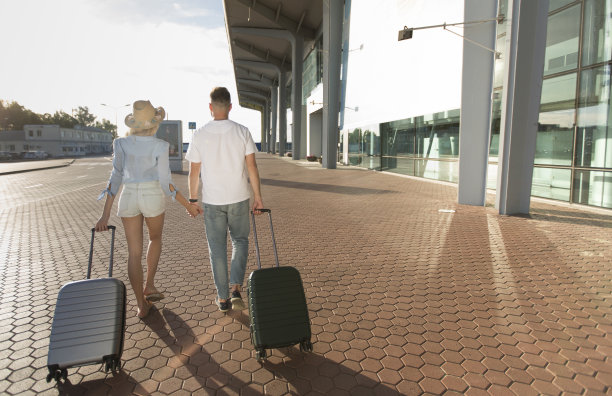 一对夫妇拿着行李在机场大楼附近散步图片下载