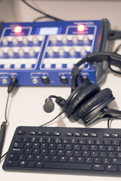 工作室的时间。特写耳机与其他专业录音室设备。麦克风播客和工作室耳机上的电脑键盘上的黑色背景，水平框架库存照片。图片下载