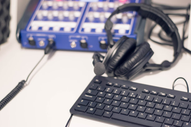 工作室的时间。特写耳机与其他专业录音室设备。麦克风播客和工作室耳机上的电脑键盘上的黑色背景，水平框架库存照片。图片下载