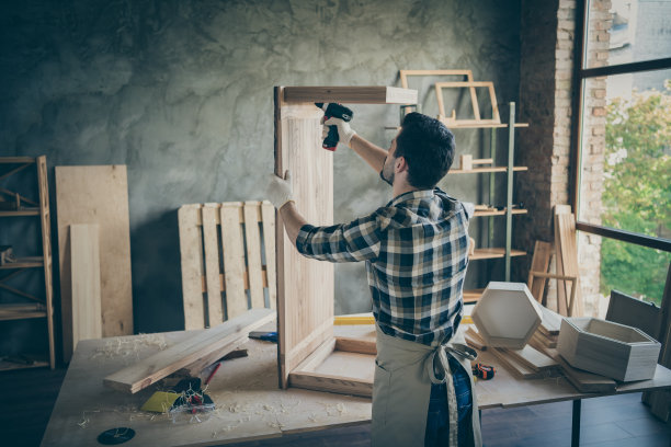 背面，背面，侧面的照片，专注的专业硬木工人固定板桌子，使用电子钻，要修理装饰家具在家里的房子车库图片下载