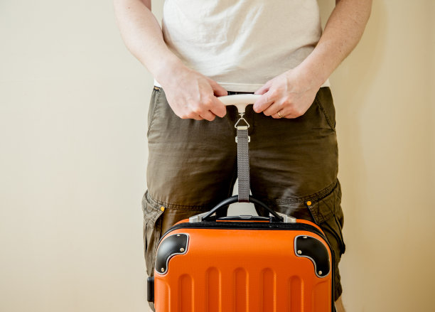 男子游客在家里使用数字行李秤称重行李，以避免超重行李在机场的概念。减少旅行的压力。图片下载