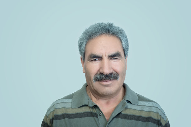 站在灰色背景旁看着镜头的微笑的年长男人图片下载