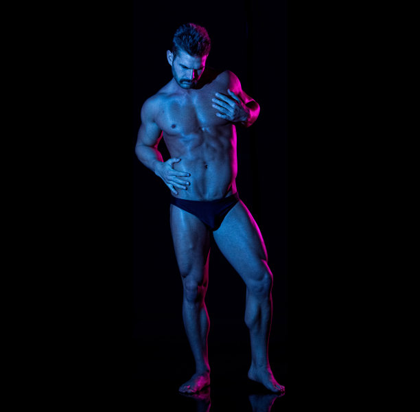 白人男性穿着男性内裤站在黑色背景前图片下载