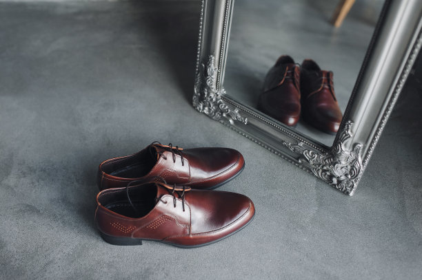 在镜子旁边的灰色地板上，放着一双崭新的棕色男式皮鞋。鞋的倒影。婚礼的照片。图片下载