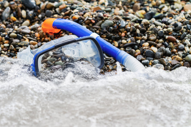 在卵石滩上潜水用的蓝色通气管和面罩图片下载