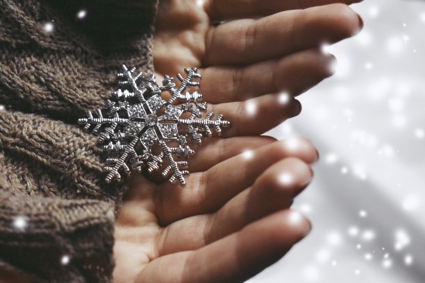 戴着棕色手套的双手捧着一片雪花图片下载