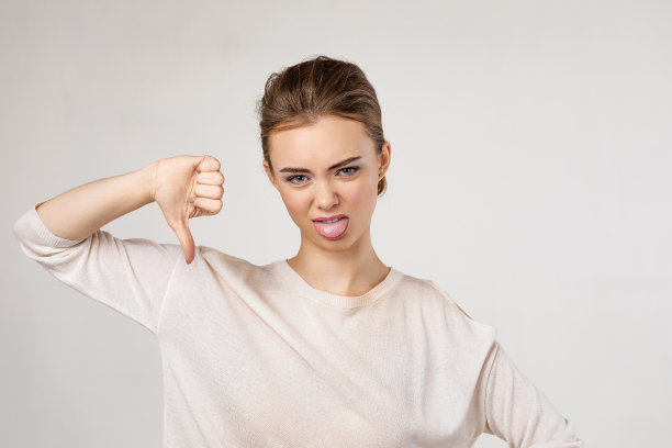 美丽的年轻女子展示拇指向下的手势图片下载