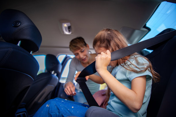 母亲教她的小女儿如何系安全带-库存照片图片下载