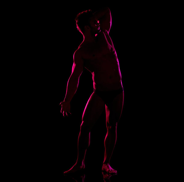 白人年轻男性穿着男性内裤站在黑人背景前图片下载