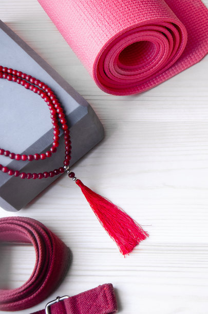 瑜伽用品背景：卷起的运动垫、木制念珠、瑜伽砖和腰带图片下载