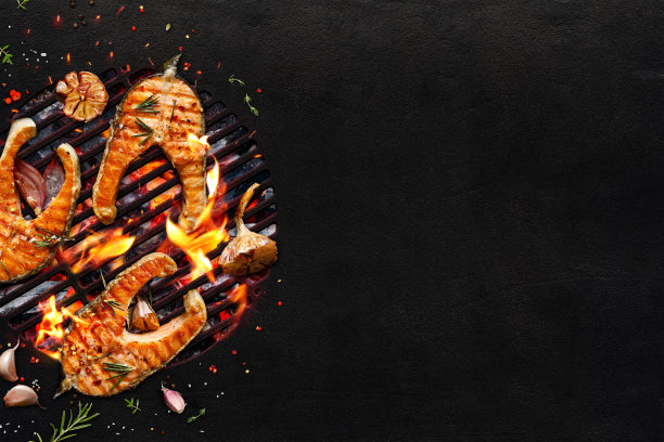烤鲑鱼排和蔬菜在烤架上的黑色背景与拷贝空间。图片下载