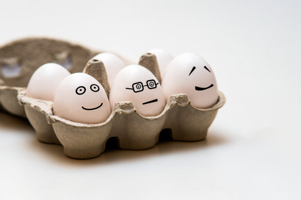 浅色背景的棕色小储物盒里，白色的鸡蛋和有趣的面孔图片下载