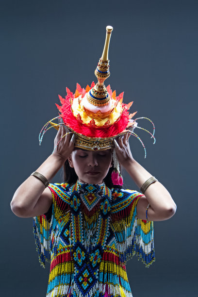 美丽的女人穿着由彩色珠子制成的泰国南部民族舞蹈服装，在纯色背景上取下头饰图片下载