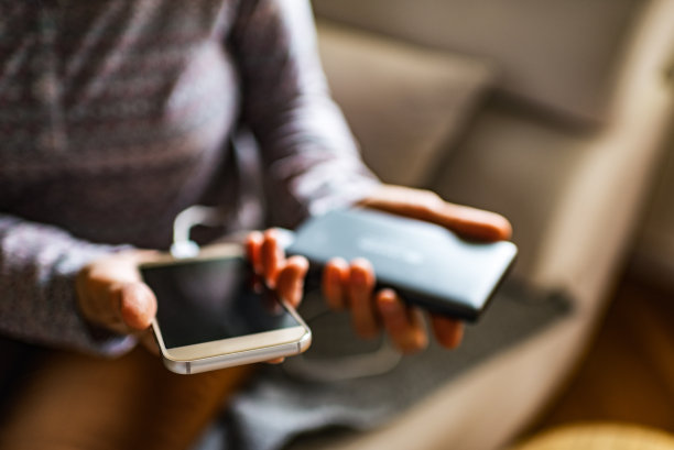 特写的妇女持有移动充电器的智能手机图片下载