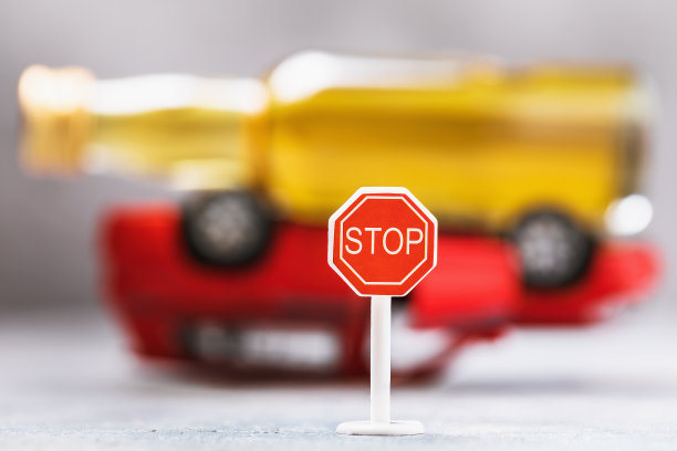 倒置汽车上的路标和威士忌酒瓶：酒驾主题图片下载