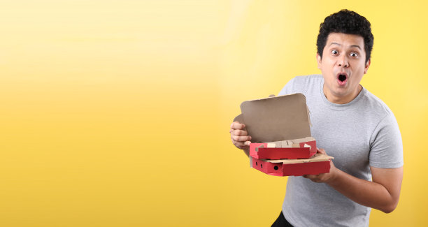 亚洲年轻男人手持披萨外卖盒惊讶表情图片下载