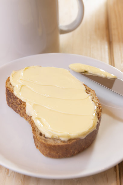 涂了黄油的面包放在白盘子里。图片下载