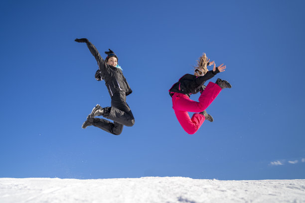 年轻的滑雪者在雪山上嬉戏跳跃图片下载