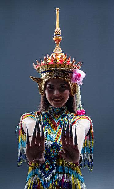 美丽的女人穿着泰国南部民族舞蹈服装，由彩色珠子制成，头上戴着头饰，练习和展示表演，模特在纯色背景上摆姿势图片下载