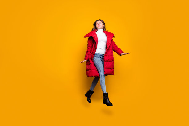 全身的个人资料照片迷人的女士跳高步行街惊人的阳光明媚的秋天的一天穿牛仔裤鞋子白色套衫红色长大衣孤立的黄色背景图片下载
