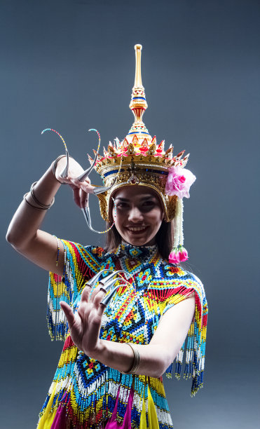 美丽的女人穿着泰国南部民族舞蹈服装，由彩色珠子制成，头上戴着头饰，练习和展示表演，模特在纯色背景上摆姿势图片下载