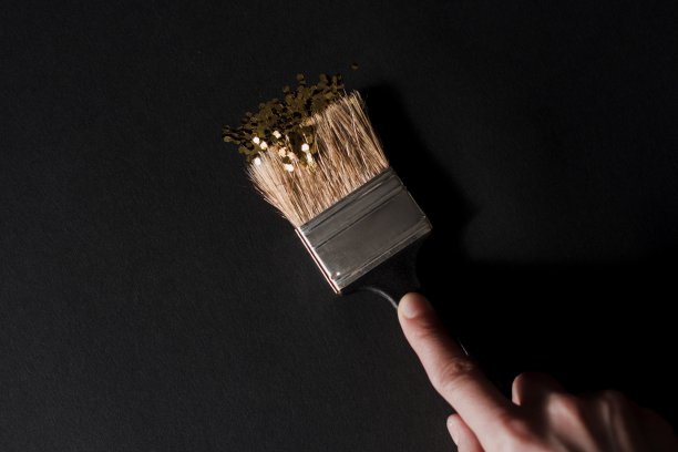 年轻女子把黑色的墙漆成金色图片下载