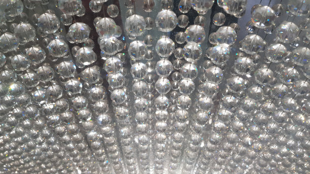 模糊发光的水晶珠子近距离模糊的背景。镶着宝石的玻璃珠成排地挂着。闪亮的宝石珠背景。玻璃材质closep。图片下载