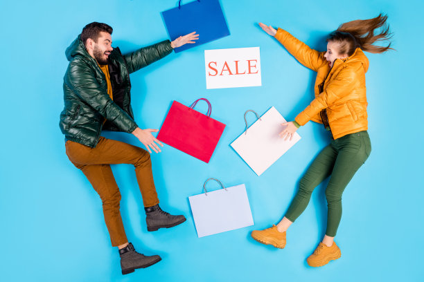 上面的高角度视角，全长，身体尺寸，侧面照片，愉快积极的配偶躺在包装和平板电脑之间，他们孤立的淡色蓝色背景图片下载