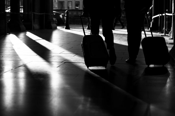 在伦敦圣潘克拉斯车站可见两人提着行李箱行走，黑白相间的画面，集中在影子、影子上图片下载