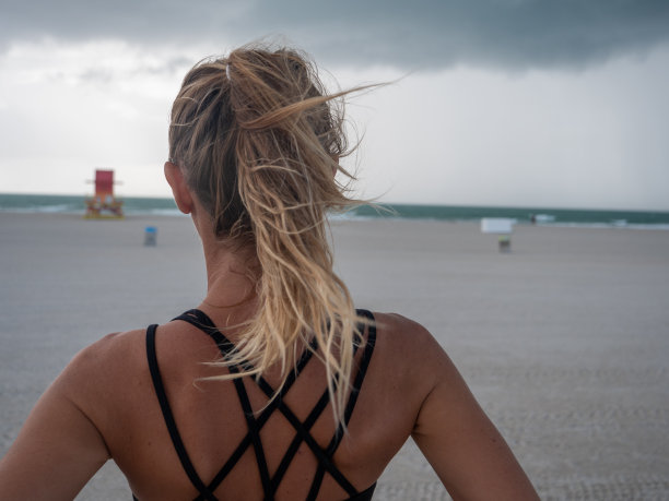 在海滩上思考海洋的运动年轻女人，迈阿密海滩图片下载