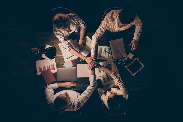 四位商业伙伴深夜在办公室内合作的俯视照片图片下载