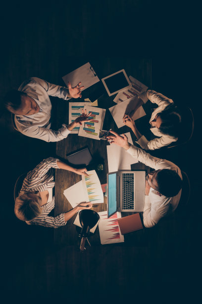 高角度以上视图垂直照片四个商业伙伴坐在对面桌子工作到深夜谈论新启动的细节举行方案统计正装灯灯光室内图片下载